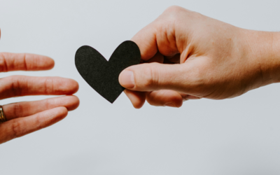 Mano che porge un cuore nero ad un'altra mano.