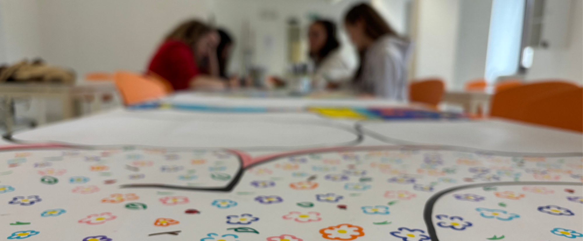 un cartellone pieno di fiori disegnati e sullo sfondo delle ragazze 