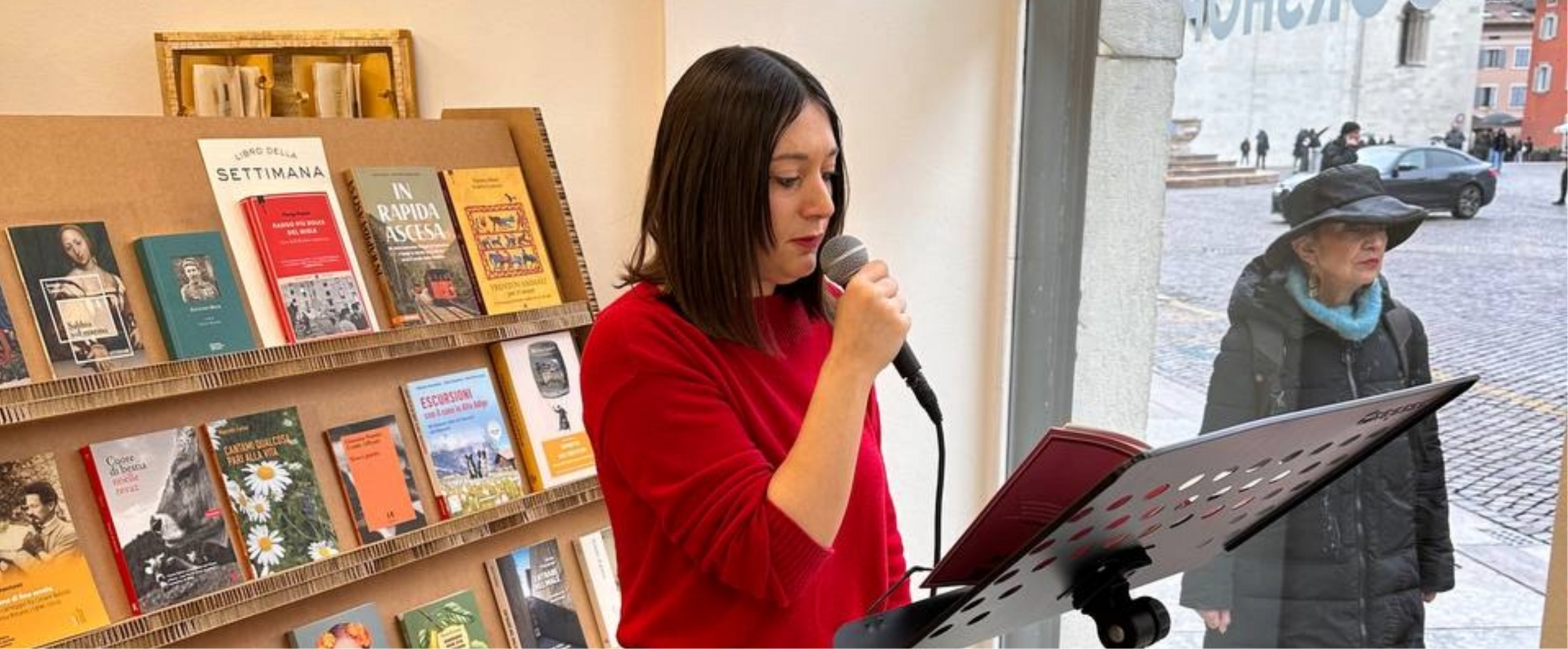 Una ragazza che legge da una vetrina con lo sfondo di uno scaffale di libri