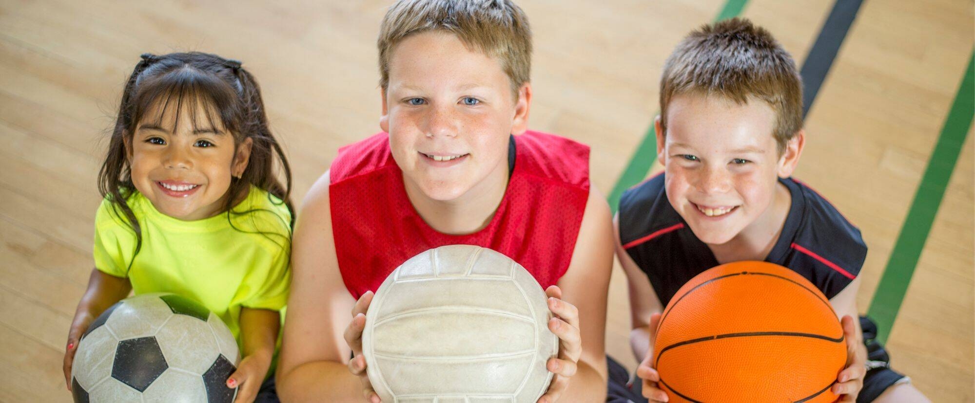 Tre bambini seduti con in mano una palla 