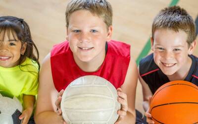 Tre bambini seduti con in mano una palla 