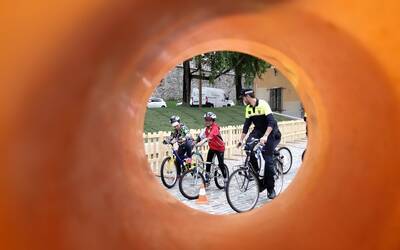 un agente di polizia locale in bicicletta affianca un bambino e una bambina in bicicletta lungo un percorso