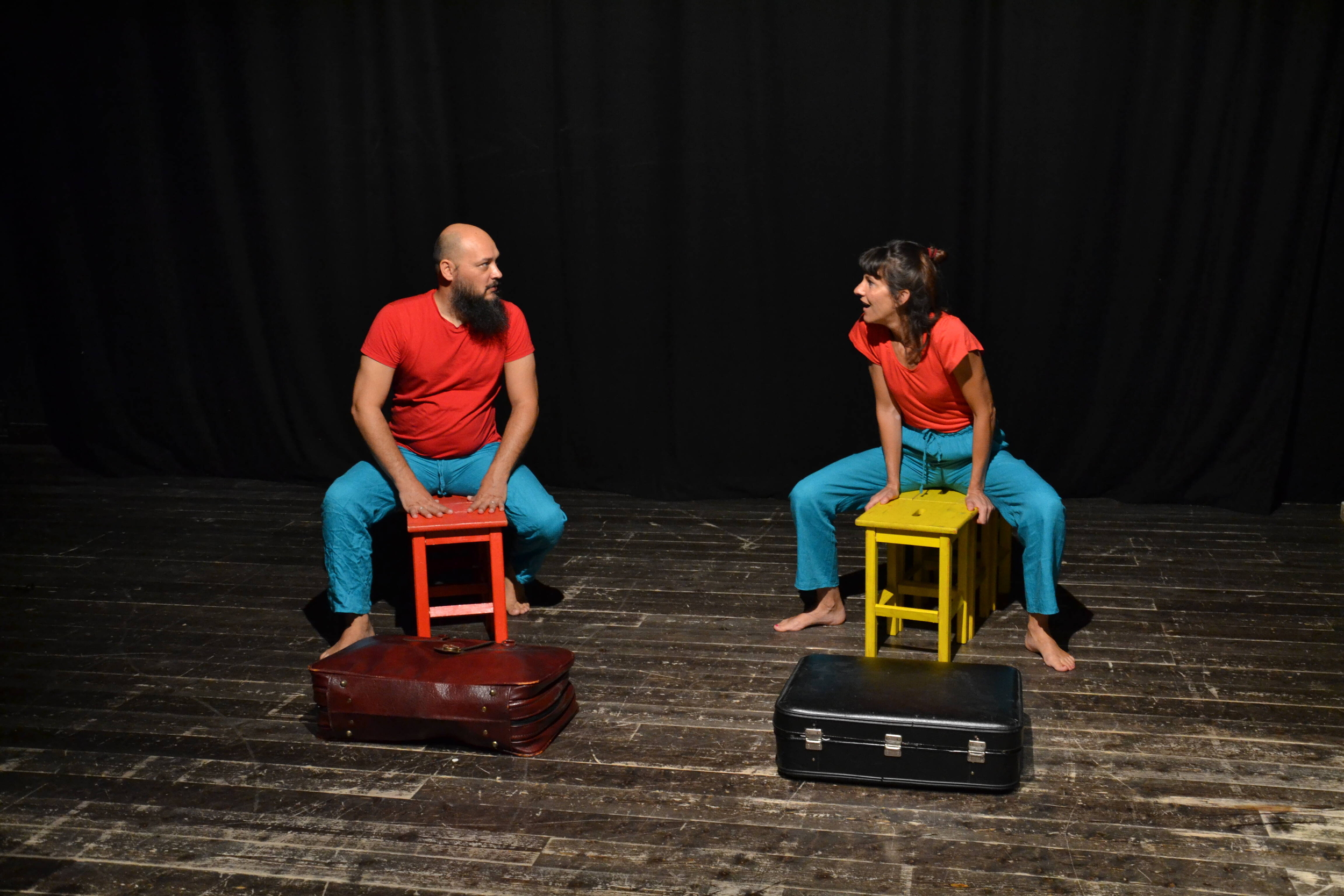 due persone (un uomo e una donna) sul palco sedute su sgabelli colorati si guardano uno a fianco all'altro