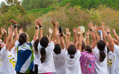 Un gruppo di ragazzi e ragazze all'aperto che alzano le mani in alto