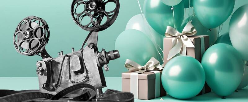 Sulla sinistra c'è una vecchia cinepresa, mentre sulla destra dei palloncini color turchese e dei pacchi regalo