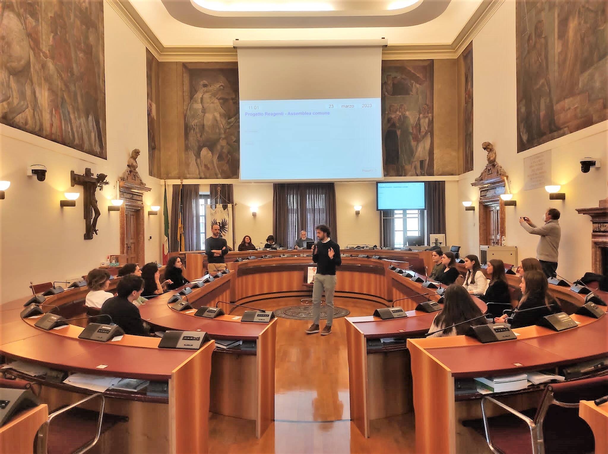 alcuni ragazzi e ragazze seduti all'interno della sala del consiglio comunale