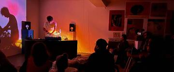 stanza al buio, un ragazzo sta suonando musica elettronica e gli altri lo ascoltano