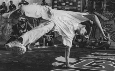 Ragazzo che balla per strada mentre altre persone lo guardano.