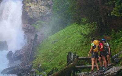una cascata in mezzo al bosco e due persone sulla destra che la guardano