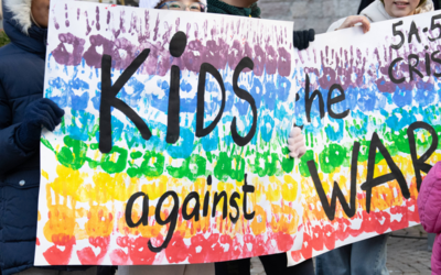 Uno striscione con i colori dell'arcobaleno sorretto da dei bambini in piazza