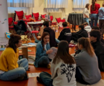 Ragazzi e ragazze a gruppi che parlano con operatori di associazioni in una palestra