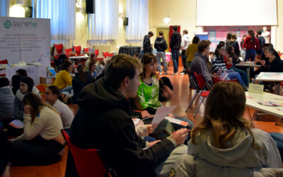 Ragazzi e ragazze a gruppi che parlano con operatori di associazioni in una palestra