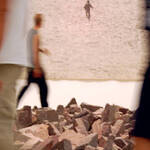 cinque ragazzi camminano intorno ad un'installazione artistica costituita da pietre deposte per terra