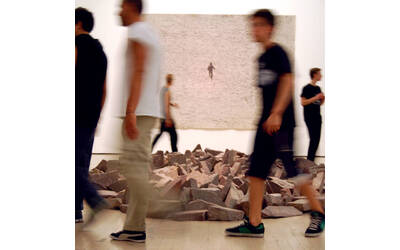 cinque ragazzi camminano intorno ad un'installazione artistica costituita da pietre deposte per terra