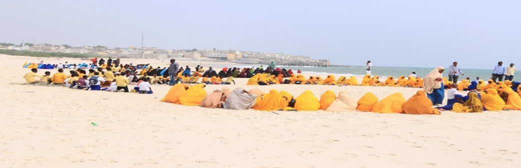 Dei ragazzi e delle ragazze somale che fanno lezione in riva all'Oceano