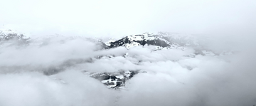 La fotografia della cima di una montagna, tra neve e nebbia