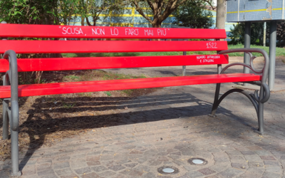 una panchina rossa in un parco con il numero antiviolenza 1522
