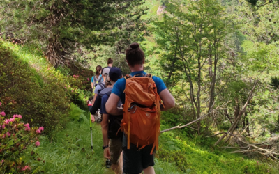 Alcuni ragazzi e ragazze di schiena e in fila indiana che percorrono un sentiero di montagna