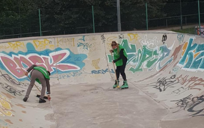 due persone sui pattini a rotelle con delle scope in mano sulla pista da skate del parco di Trento