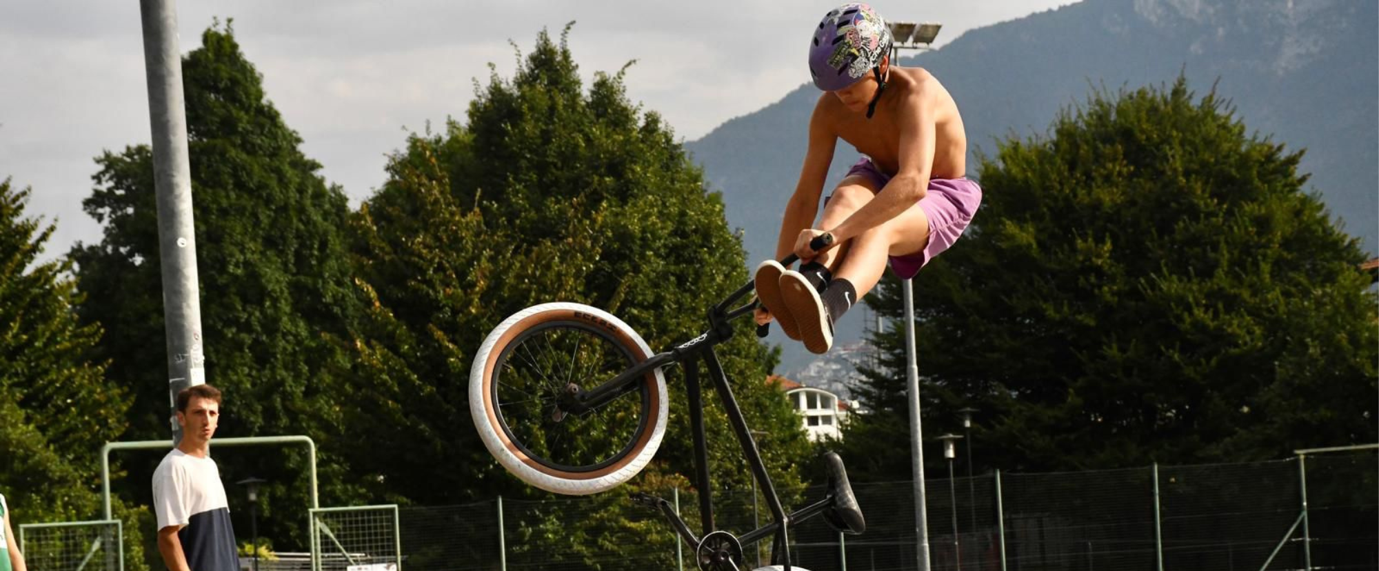 Un ragazzo che effettua un salto acrobatico sulla bmx allo skatepark di Trento