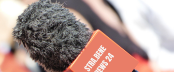 un microfono da intervista in esterni con la scritta "strabene news 24"