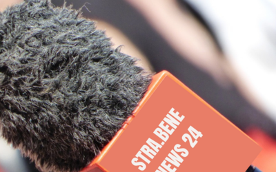 un microfono da intervista in esterni con la scritta "strabene news 24"