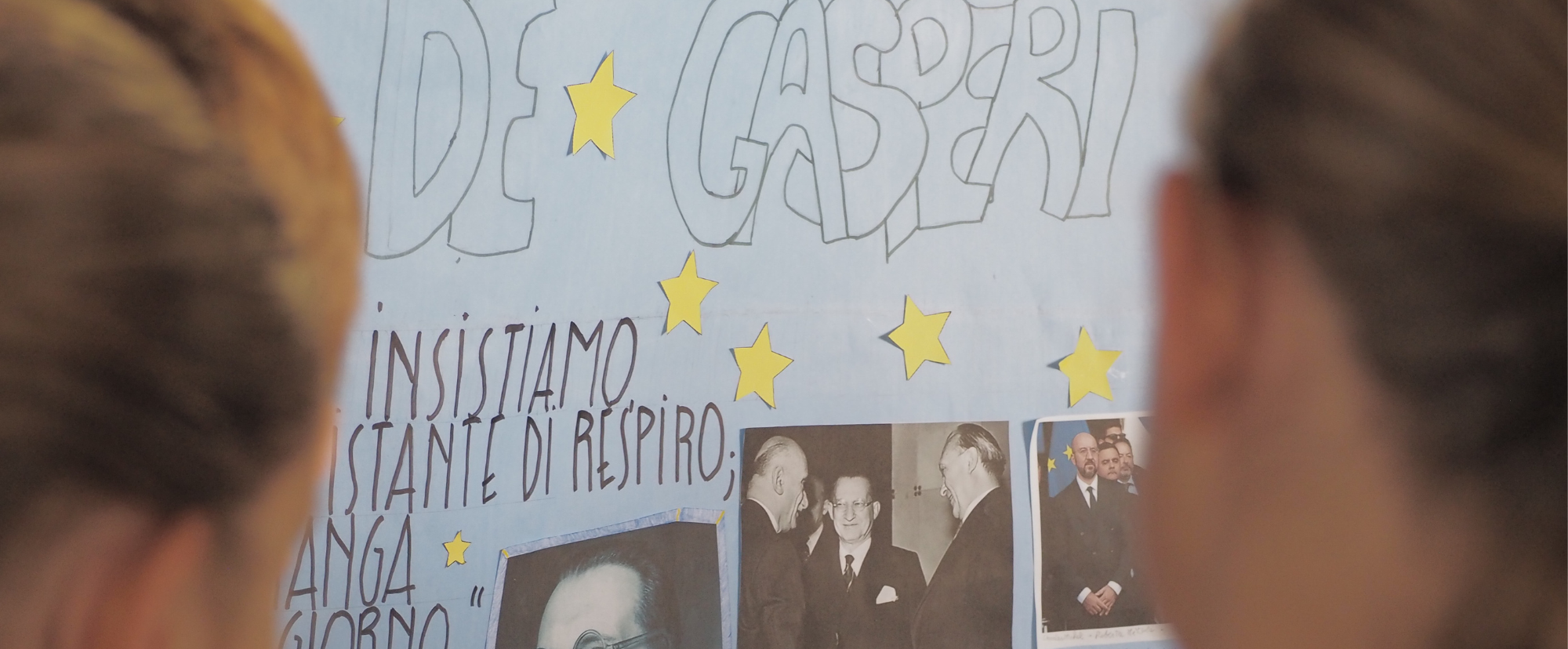 Una ragazza e un ragazzo di spalle che osservano un cartellone 