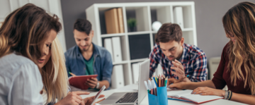 cinque giovani lavorano insieme sorridendo 