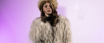 Una donna con un cappello di pelliccia su uno sfondo rosa