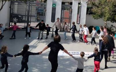 un cerchio di bambini che danza attorno ad uno striscione di pace